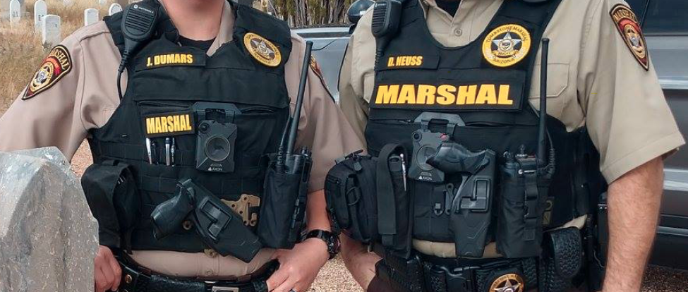 Two armed Tombstone Marshals with square Axon body-worn cameras in the center of their vests.