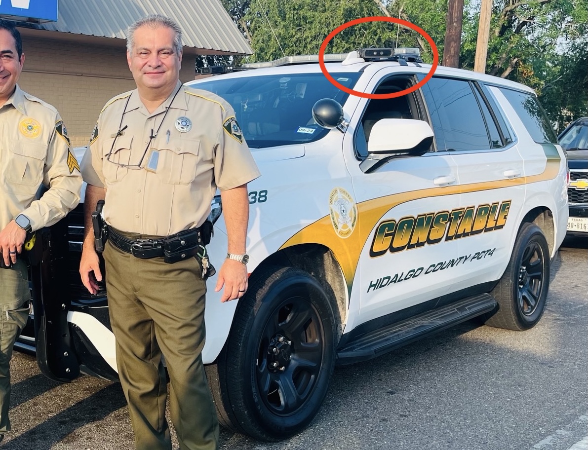 An officer stands beside patrol car. Red circle identifies mobile ALPR An officer stands beside patrol car. Red circle identifies mobile ALPR