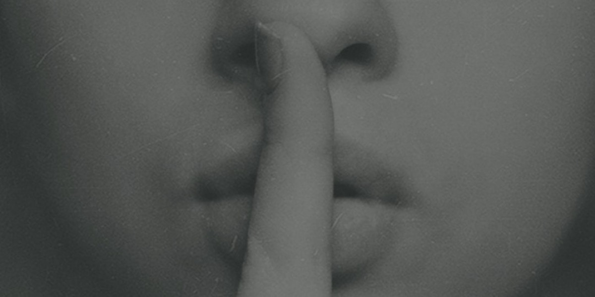 black and white image of a person with their fingers to their lips