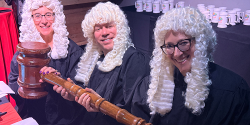 Cindy Cohn, Mike Masnick, and Nicole Ozer wear judge robes and white wigs, holding a giant gavel.